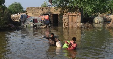 People carry their belongings out from their flooded home in Shikarpur, Sindh province, Pakistan, Aug. 31, 2022. (AFP Photo)