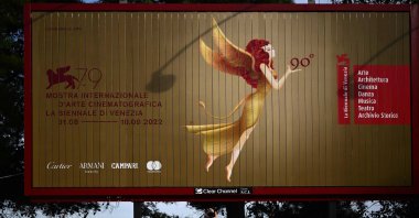 A festival goer takes photos under a billboard with the festival&#039;s logo at Lido di Venezia in Venice, Italy, on the eve of the opening of the 79th Venice International Film Festival, Aug. 30, 2022. (AFP)