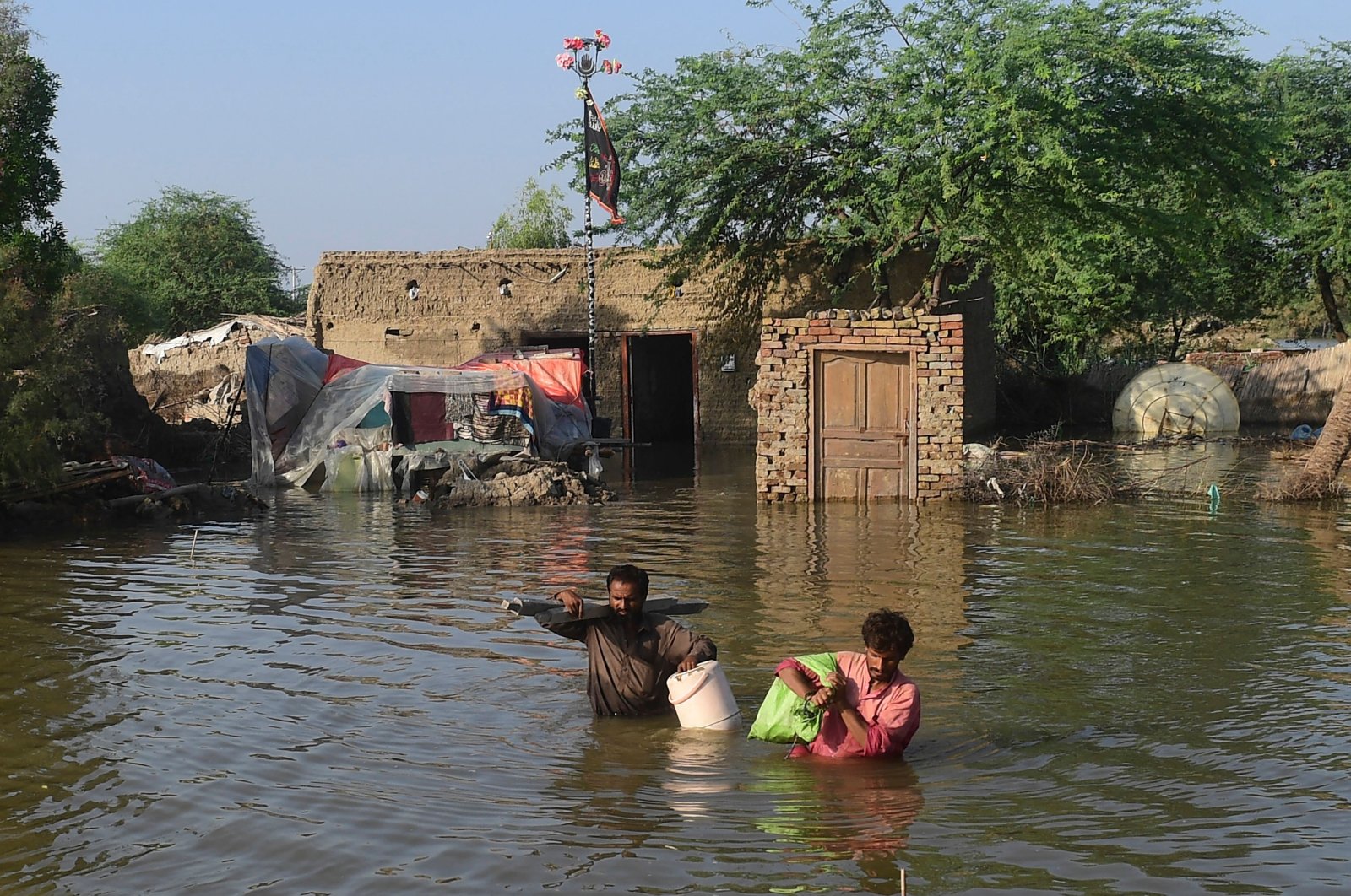 People carry their belongings out from their flooded home in Shikarpur, Sindh province, Pakistan, Aug. 31, 2022. (AFP Photo)
