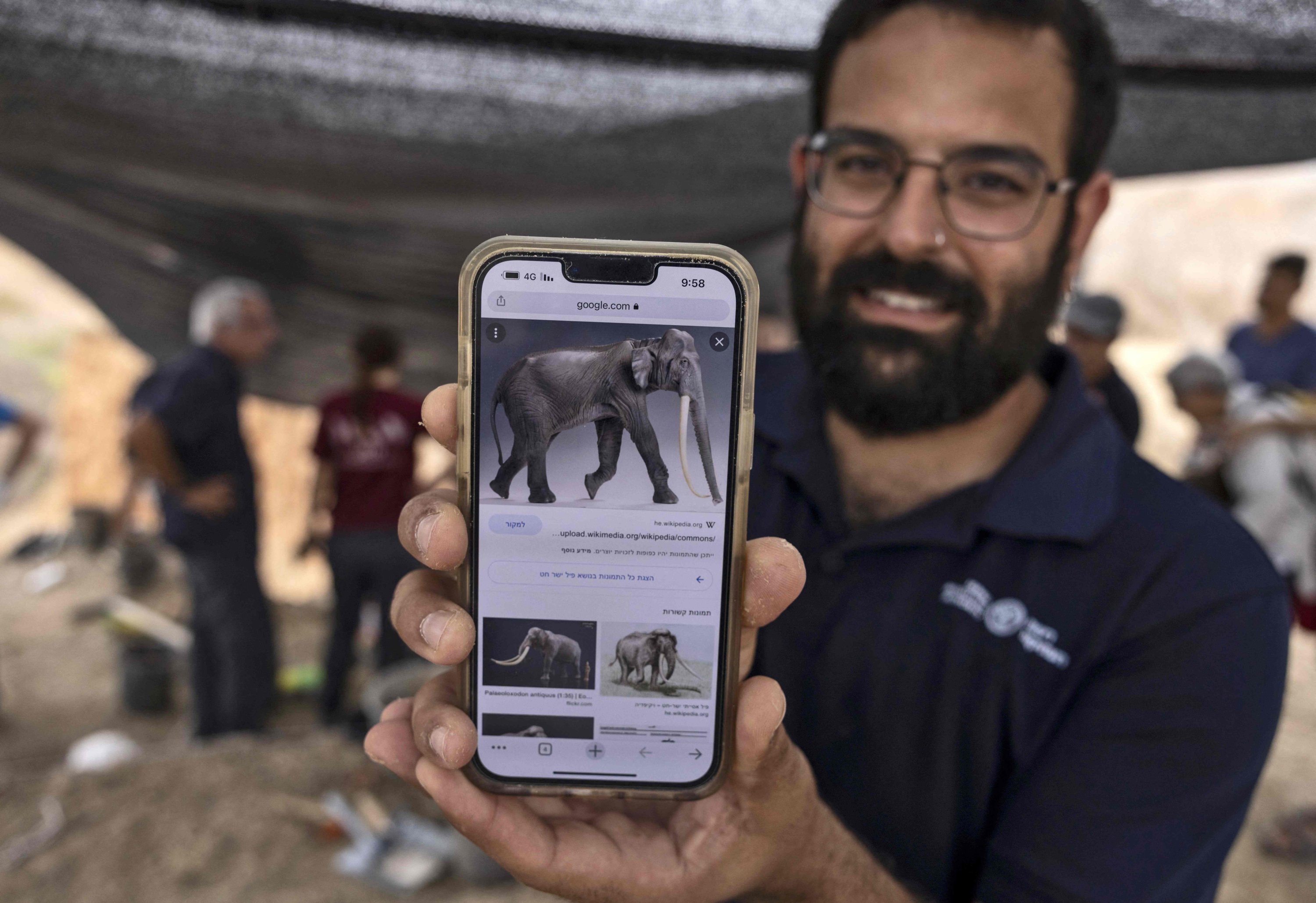 Avi Levy, arkeolog dari Israel Antiquities Authority menunjukkan gambar gajah purba bergading lurus (Palaeoloxodon antiquus), di lokasi ditemukannya gading sepanjang 2,5 meter, dekat Kibbutz Revadim di Israel selatan, 31 Agustus 2022 (Foto AFP)