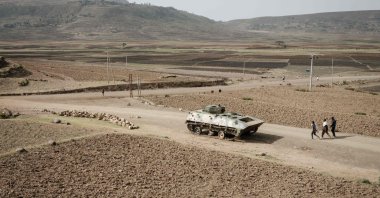 In this file photo taken on June 20, 2021, People walk near a tank of the Ethiopian army abandoned on the road near Dengolat, southwest of Mekele in the Tigray region, Ethiopia. (AFP Photo)