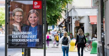 People walk next to election poster of the leader of the Social Democrats and Swedish Prime Minister Magdalena Andersson, in Stockholm, Sweden, Aug. 30, 2022. (AFP Photo)