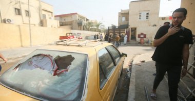 A man walks past a damaged vehicle on a street littered with the aftermath of clashes among rival Shiite Muslim militants in Basra, Iraq, Sept. 1, 2022. (Reuters Photo)