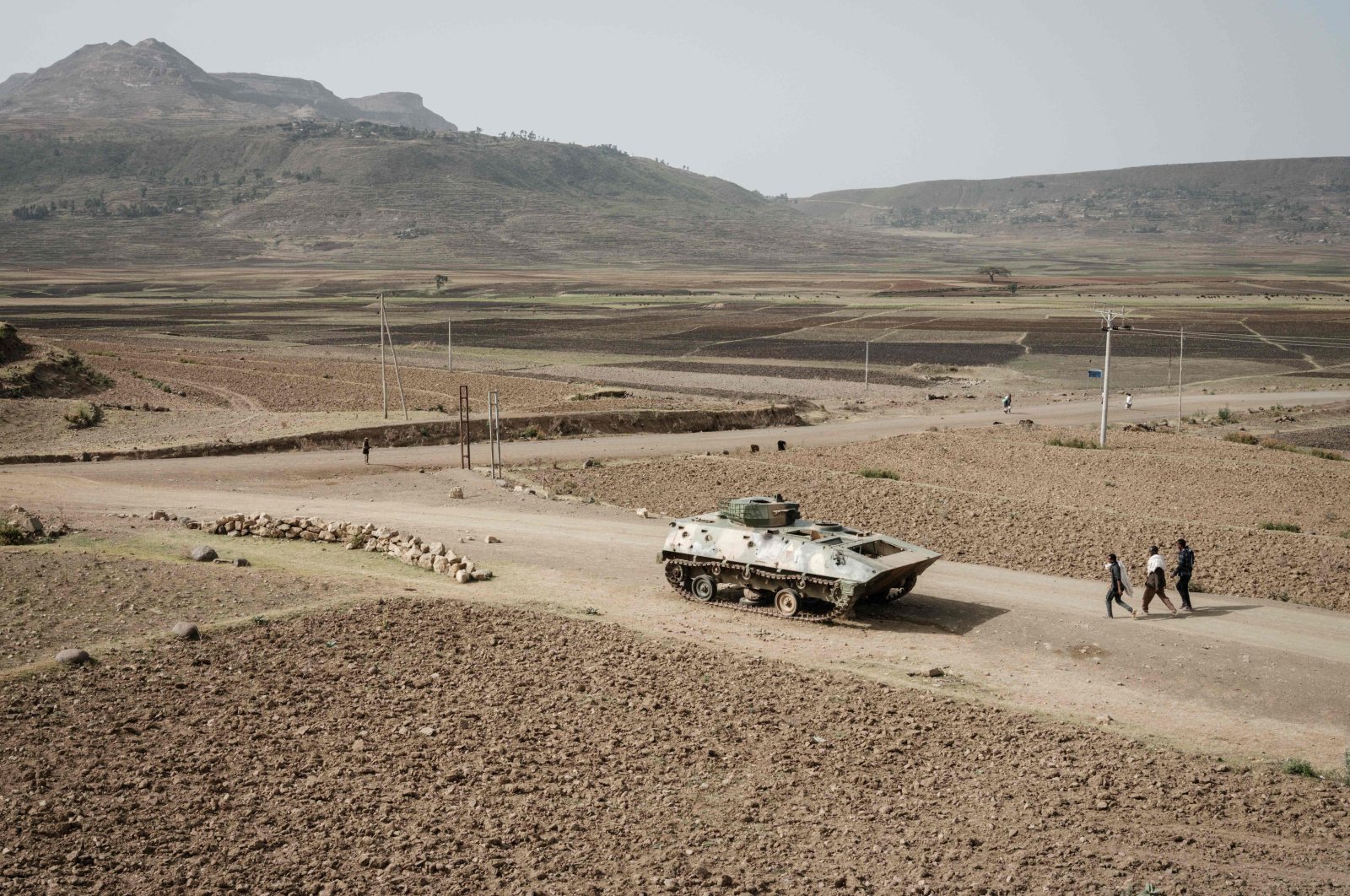 In this file photo taken on June 20, 2021, People walk near a tank of the Ethiopian army abandoned on the road near Dengolat, southwest of Mekele in the Tigray region, Ethiopia. (AFP Photo)