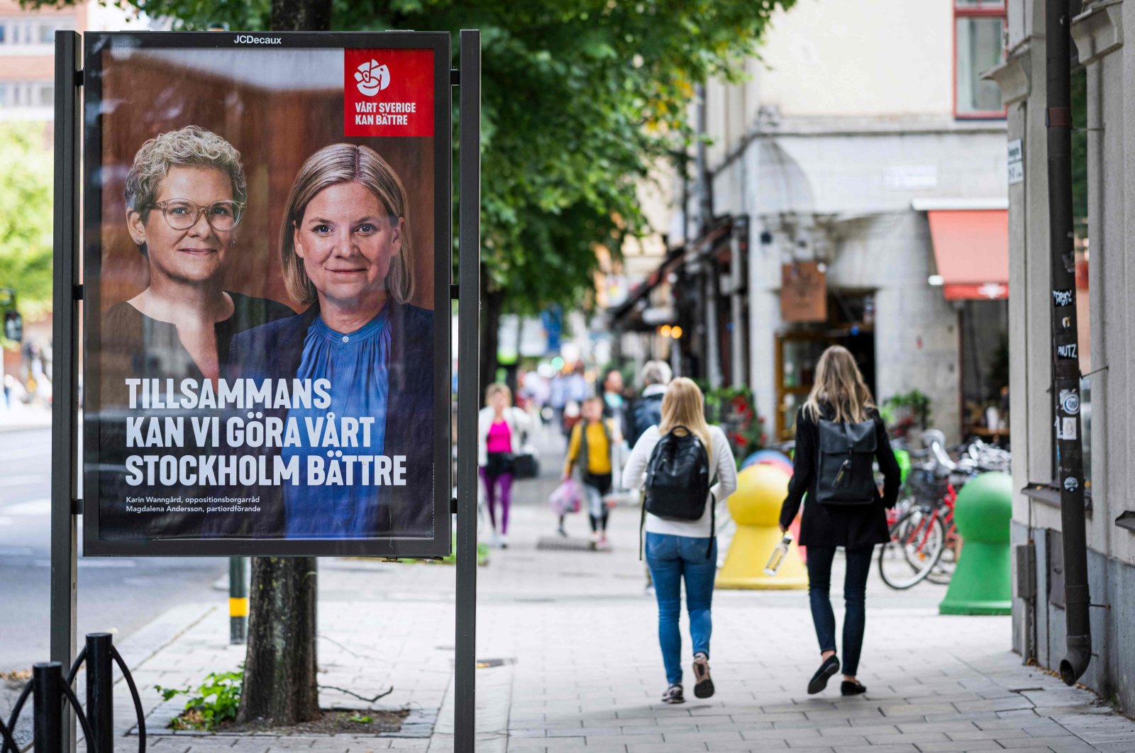 People walk next to election poster of the leader of the Social Democrats and Swedish Prime Minister Magdalena Andersson, in Stockholm, Sweden, Aug. 30, 2022. (AFP Photo)