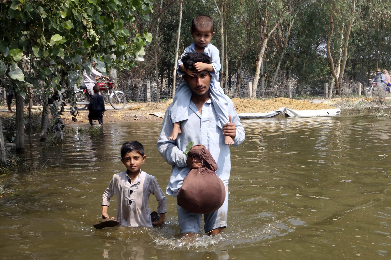 A man carries his son as he wades through floodwaters in Charsadda, Pakistan, Sept. 1, 2022. (AP Photo)