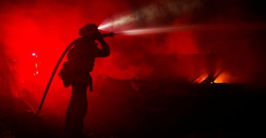 A fire fighter hoses down hotspots in homes that were burnt as the Mill Fire burns near Weed, California, U.S., Sept. 2, 2022. (Reuters Photo)