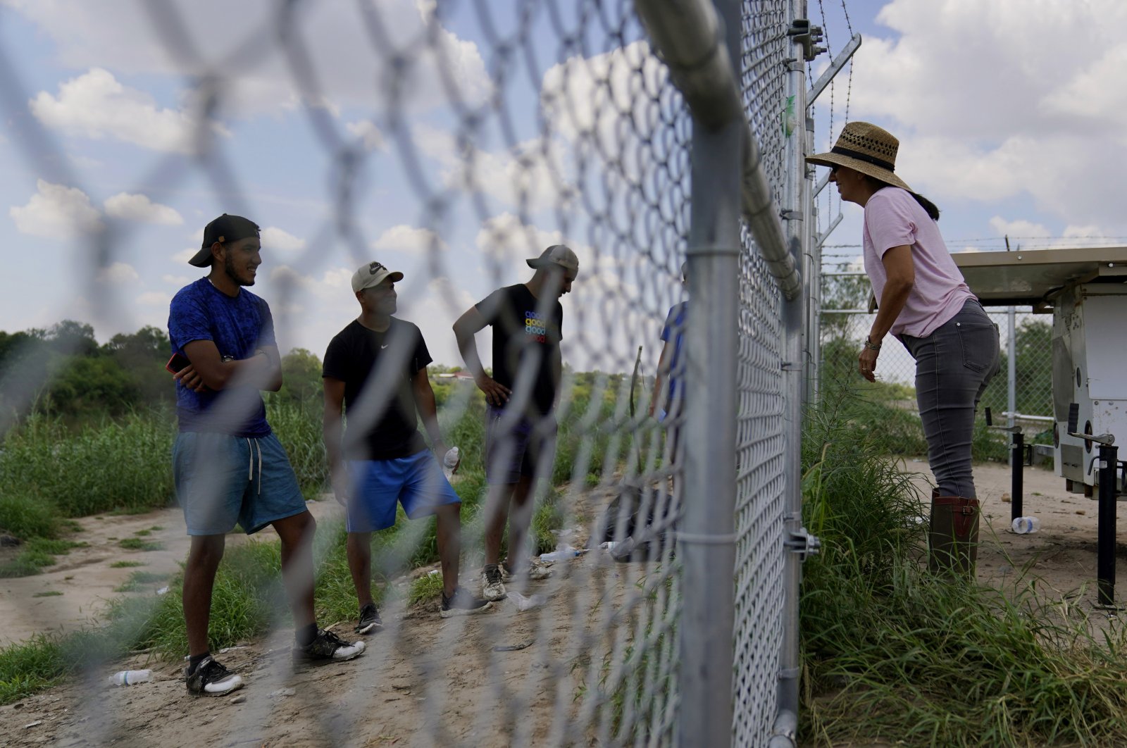Magali Urbina (R) talks through her fence to migrants who crossed the Rio Grande illegally at her pecan farm, Texas, U.S., Aug. 26, 2022. (AP Photo)