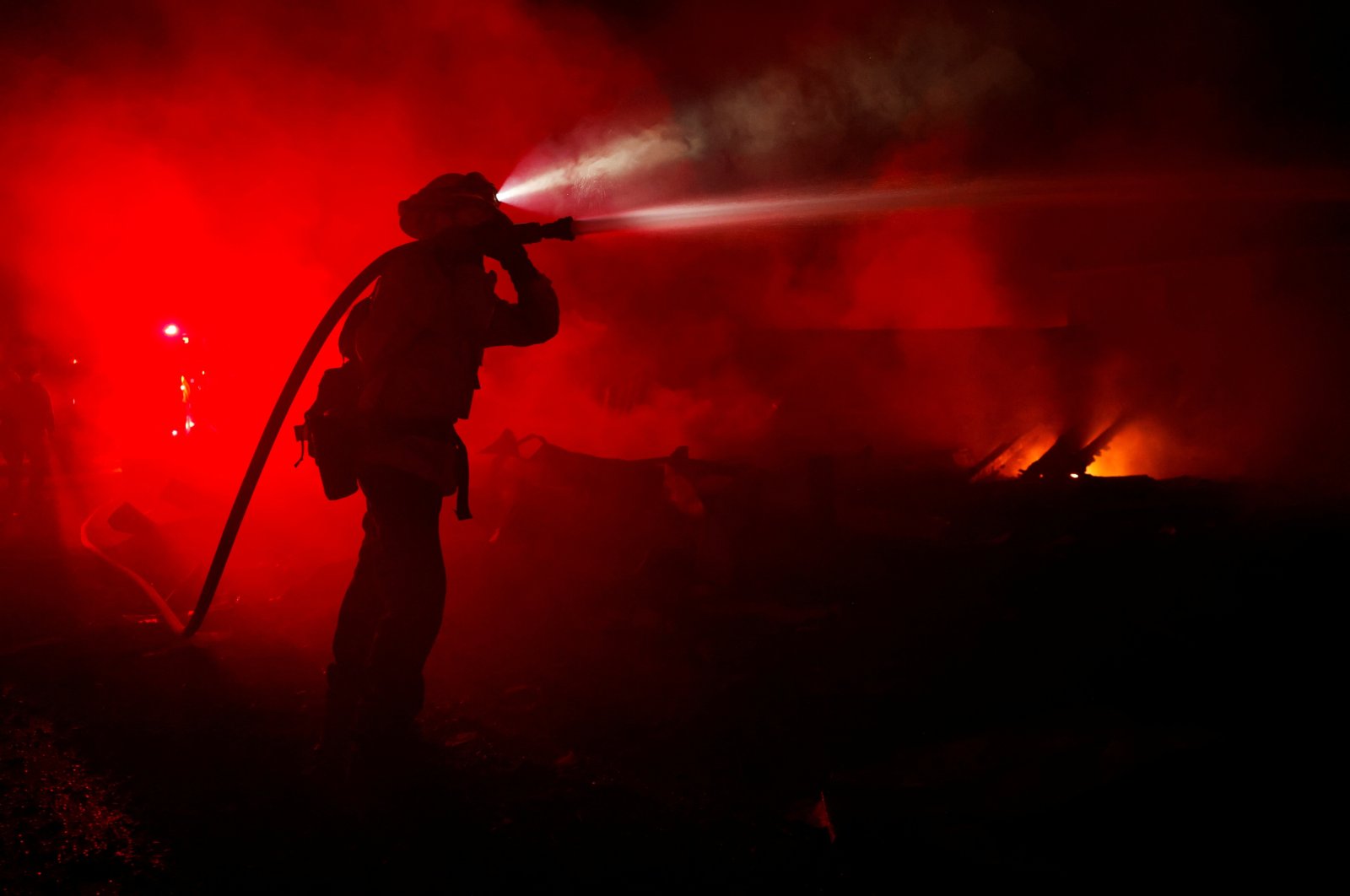 A fire fighter hoses down hotspots in homes that were burnt as the Mill Fire burns near Weed, California, U.S., Sept. 2, 2022. (Reuters Photo)