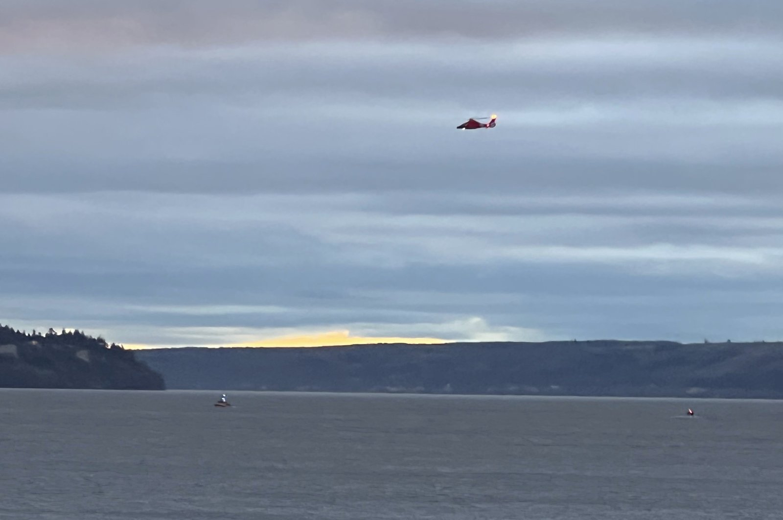 A Coast Guard helicopter searches the area where a floatplane crashed near Whidbey Island, Washington, U.S., Sept. 4, 2022. (Courtney Riffkin/The Seattle Times via AP)