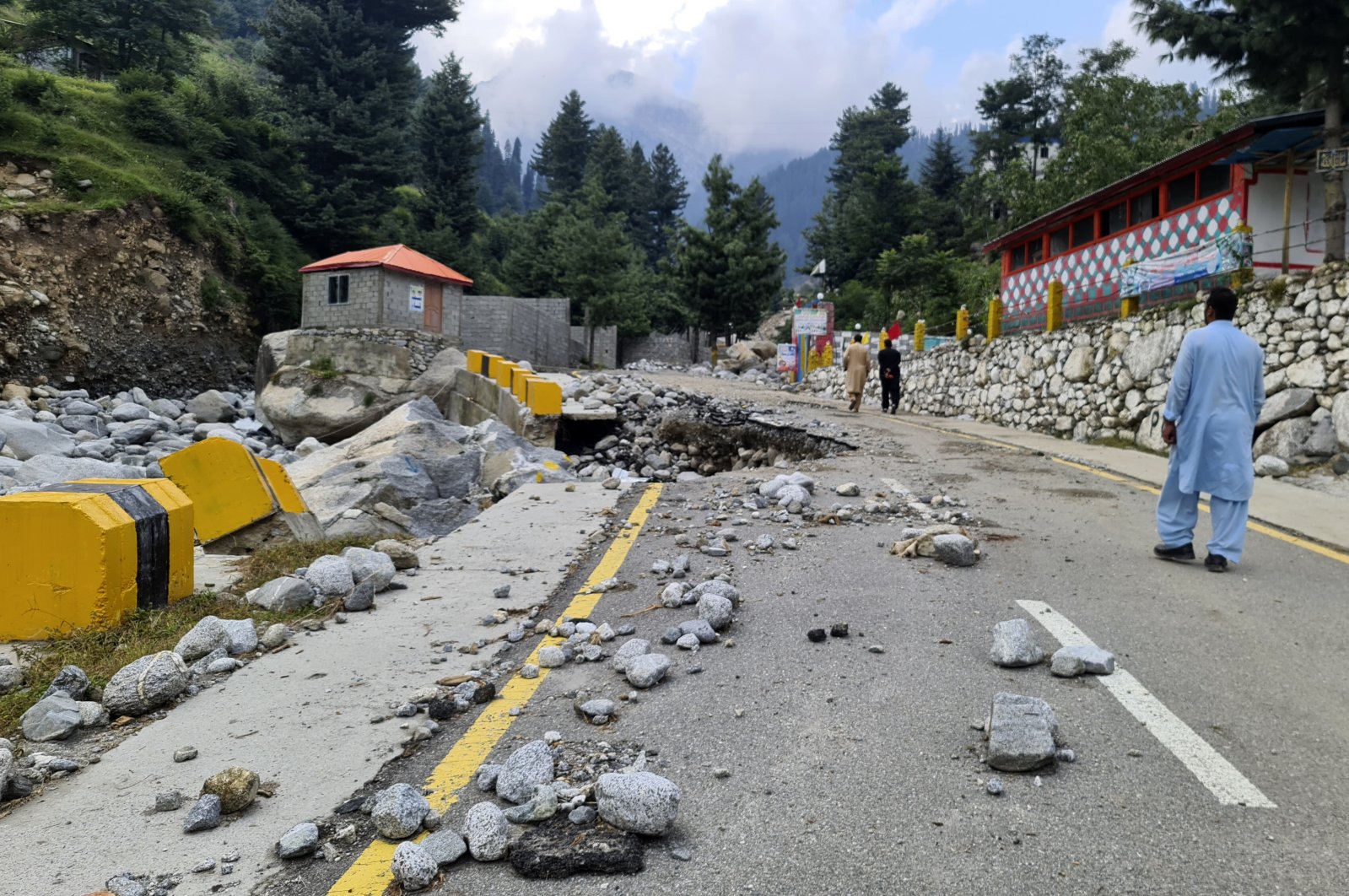 Local residents walk on a road destroyed by floodwaters in the Kalam Valley, northern Pakistan, Sept. 4, 2022. (AP Photo)