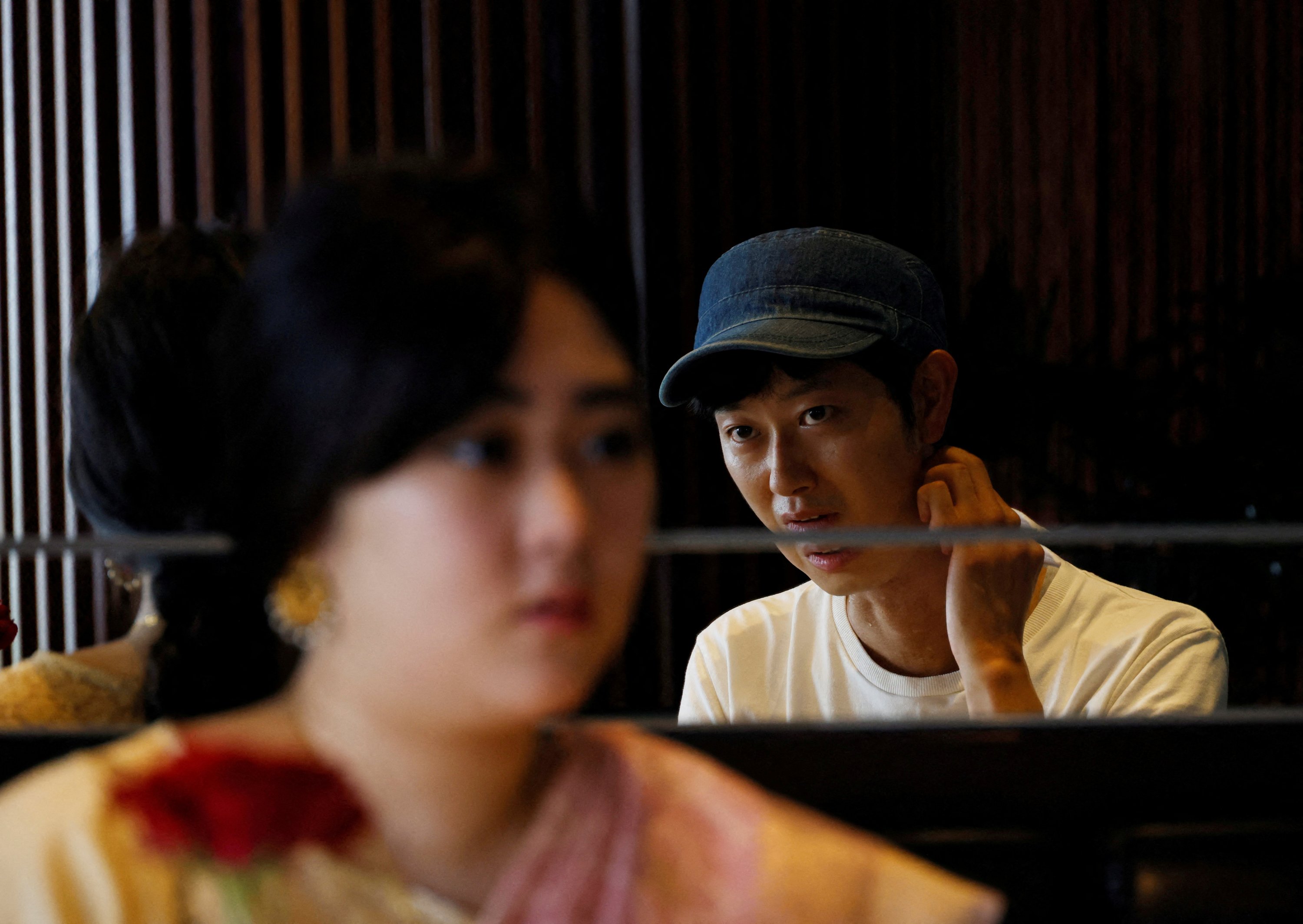 Shoji Morimoto tercermin di cermin saat berbicara dengan kliennya Aruna Chida di sebuah kafe di Tokyo, Jepang, 31 Agustus 2022. (Foto Reuters)