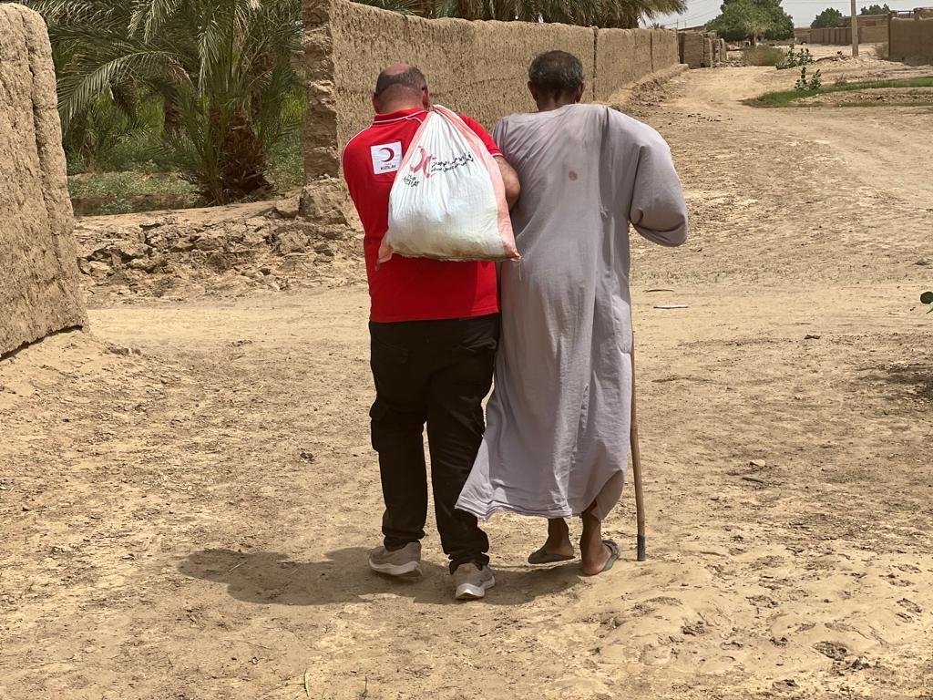 A Turkish Red Crescent worker carrying aid accompanies a local, in Dongola, Sudan, Sept. 6, 2022. (AA PHOTO) 