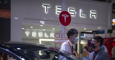Staff members talk near vehicles at a display for automaker Tesla at the China International Fair for Trade in Services (CIFTIS) in Beijing, China, Sept. 2, 2022. (AP Photo)