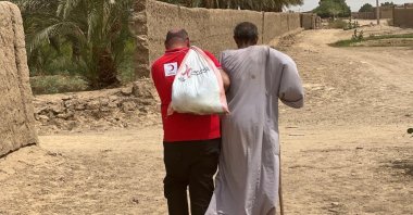 A Turkish Red Crescent worker carrying aid accompanies a local, in Dongola, Sudan, Sept. 6, 2022. (AA PHOTO) 