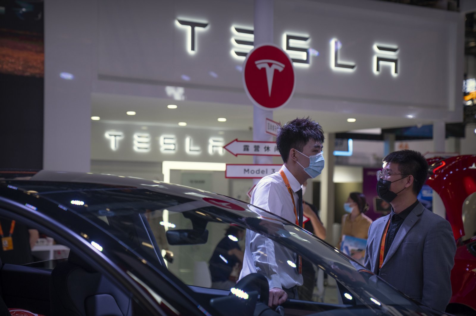Staff members talk near vehicles at a display for automaker Tesla at the China International Fair for Trade in Services (CIFTIS) in Beijing, China, Sept. 2, 2022. (AP Photo)