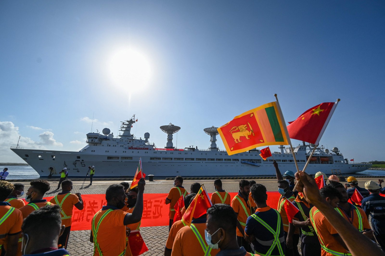 Workers wave the national flags of China and Sri Lanka upon the arrival of China&#039;s research and survey vessel, the Yuan Wang 5 at Hambantota port, Sri Lanka, Aug. 16, 2022. (AFP Photo)