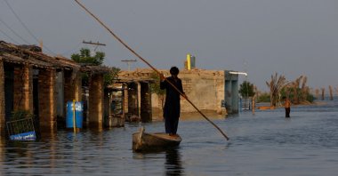 A man rows his boat as he passes through a flooded market, following rains and floods during the monsoon season in Bajara village, at the banks of Manchar lake, in Sehwan, Pakistan, Sept. 6, 2022. (REUTERS Photo)