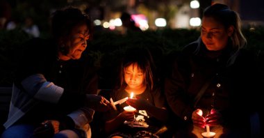 Tauriel (C),7, is flanked by her great grandmother Priscilla McLean (L) and mother Cheyenne Bird (R) during a vigil in honor of the victims of the nearby community of James Smith Cree Nation's series of stabbings in Saskatoon, Saskatchewan, Canada, Sept. 7, 2022. (AFP Photo)