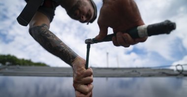 An employee of NY State Solar, a residential and commercial photovoltaic systems company, installs an array of solar panels on a roof, in the Long Island hamlet of Massapequa, N.Y., Aug. 11, 2022. (AP Photo)