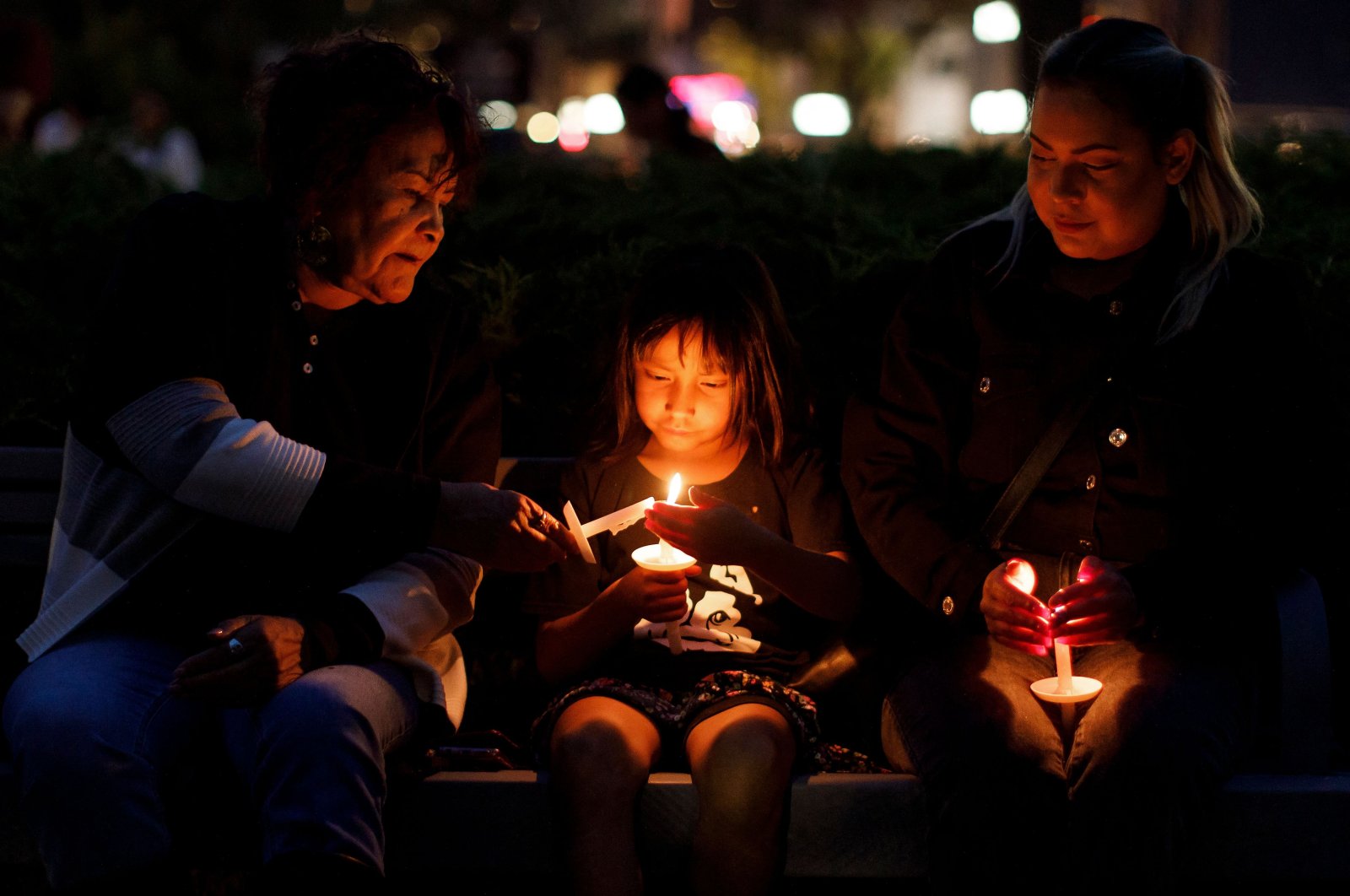 Tauriel (C),7, is flanked by her great grandmother Priscilla McLean (L) and mother Cheyenne Bird (R) during a vigil in honor of the victims of the nearby community of James Smith Cree Nation&#039;s series of stabbings in Saskatoon, Saskatchewan, Canada, Sept. 7, 2022. (AFP Photo)
