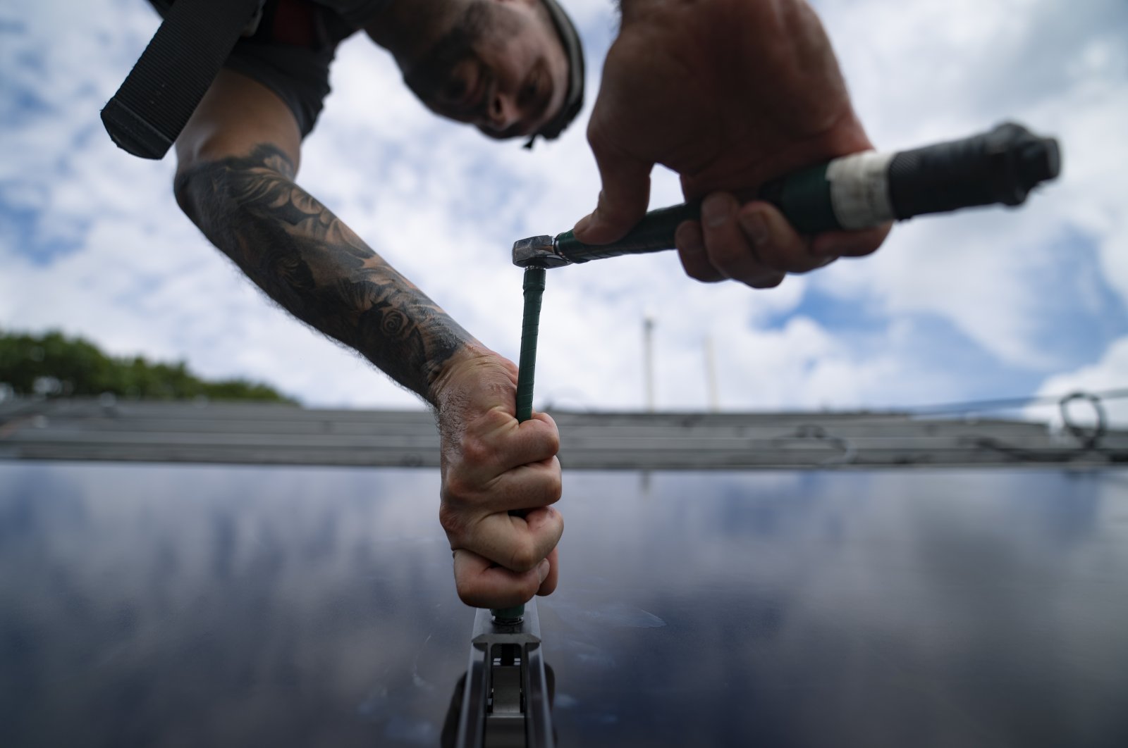 An employee of NY State Solar, a residential and commercial photovoltaic systems company, installs an array of solar panels on a roof, in the Long Island hamlet of Massapequa, N.Y., Aug. 11, 2022. (AP Photo)