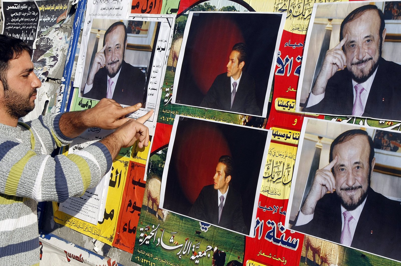A member of the Alawite community pasting on a wall pictures of Rifaat Assad (R), uncle of Syria&#039;s Bashar Assad, and his son Ribal, in Tripoli, Lebanon, Dec. 6, 2007. (AFP Photo)