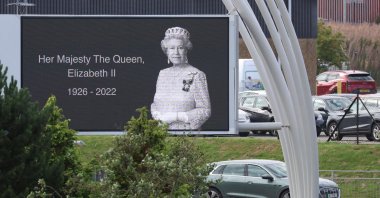 A car carrying Britain&#039;s King Charles III and Queen Camilla drives past a poster of late Queen Elizabeth outside Aberdeen International Airport to fly to London, following the passing of Britain&#039;s Queen Elizabeth, in Aberdeen, Britain, Sept. 9, 2022. (Reuters Photo)