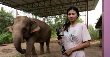 Elephant owner Siriporn Sapmak, 23, poses while holding her gear used for social media live-streaming outside her house, at Ban Ta Klang village in Surin, Thailand, April 6, 2022. (Reuters Photo)