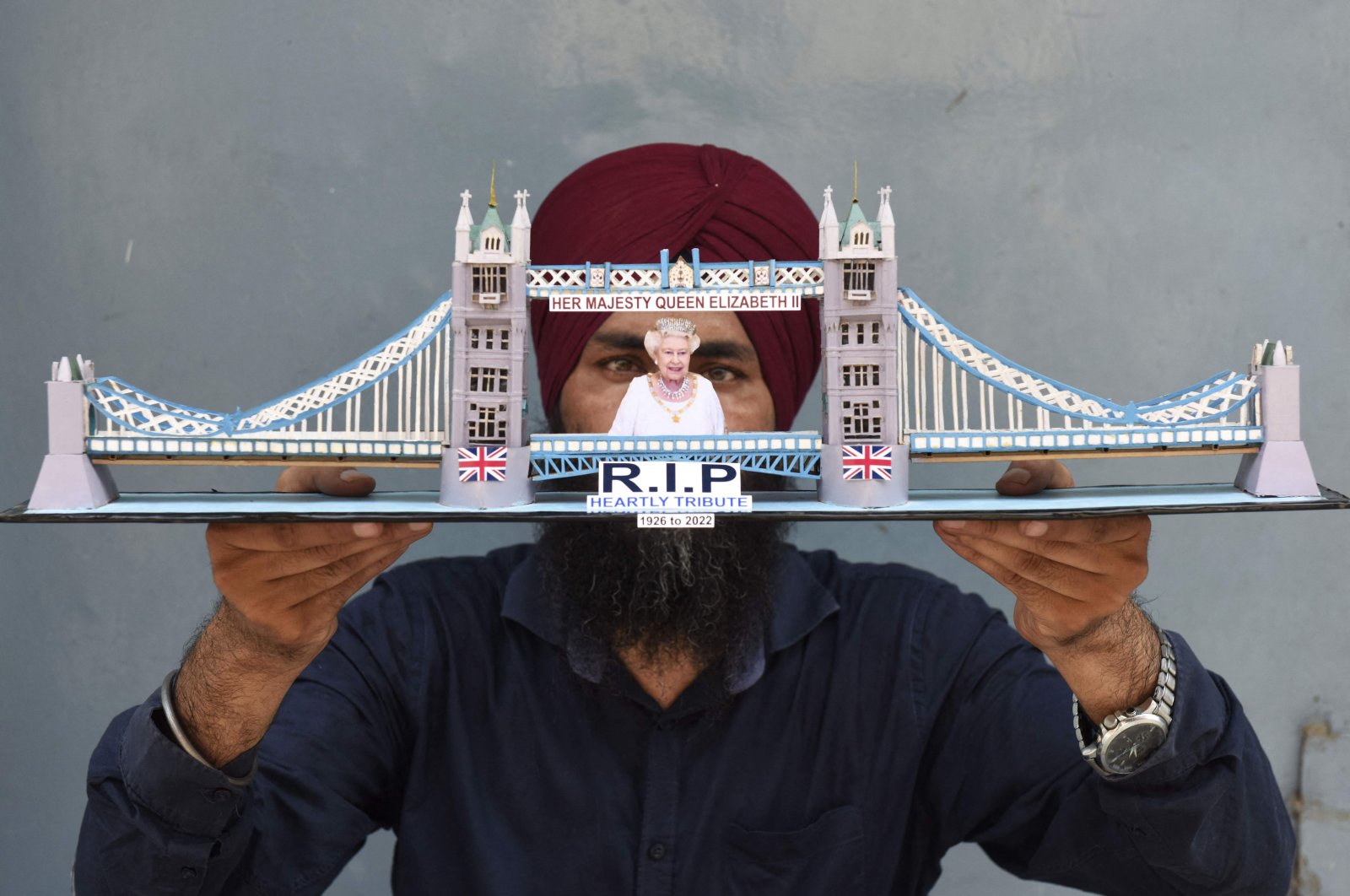 An Indian paper artist holds a model of the London Bridge as he pays tribute to the late Queen Elizabeth II, on the outskirts of Amritsar, India, Sept. 9, 2022. (AFP Photo)