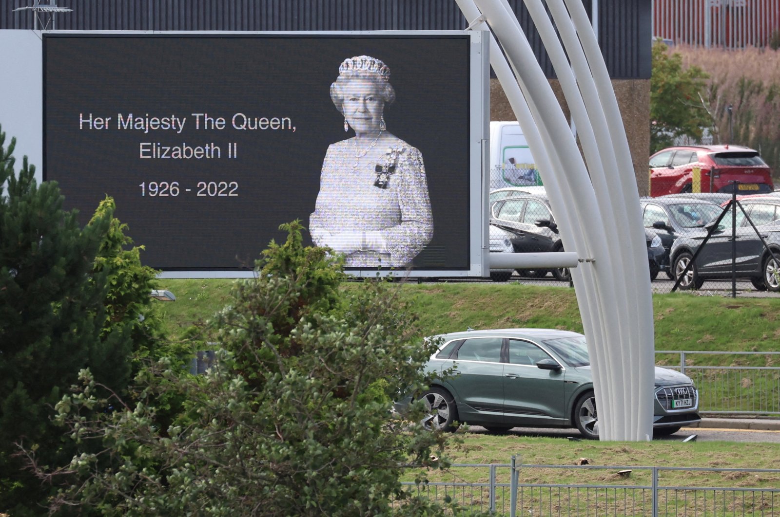 A car carrying Britain&#039;s King Charles III and Queen Camilla drives past a poster of late Queen Elizabeth outside Aberdeen International Airport to fly to London, following the passing of Britain&#039;s Queen Elizabeth, in Aberdeen, Britain, Sept. 9, 2022. (Reuters Photo)