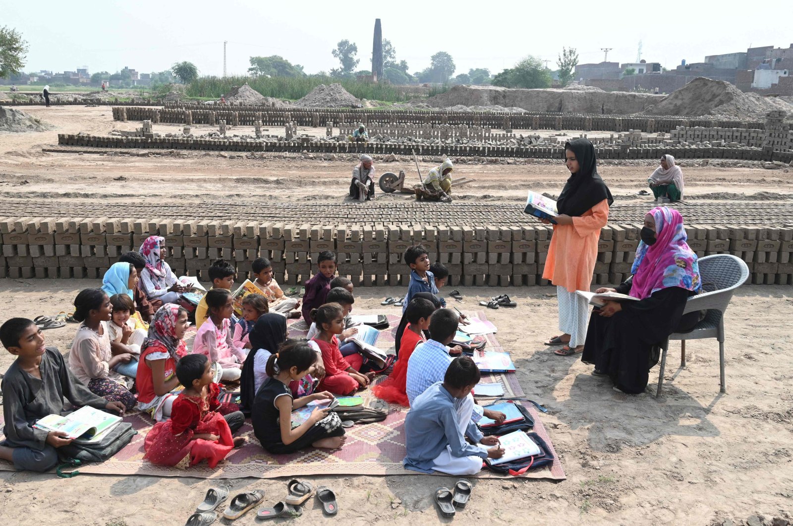 Children of brick kiln workers attend a class at a brick kiln site in Lahore, Pakistan, Sept. 8, 2022. (AFP Photo)