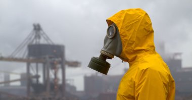 A man wearing a gas mask stands in front of a factory in an unknown location, March 3, 2010. (Alamy via Reuters)