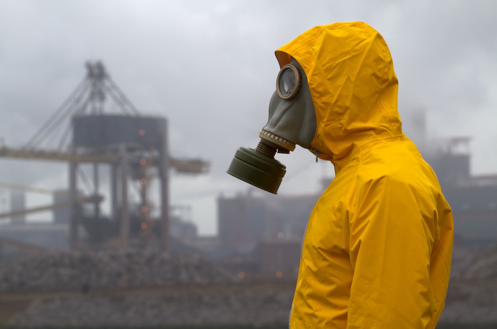 A man wearing a gas mask stands in front of a factory in an unknown location, March 3, 2010. (Alamy via Reuters)