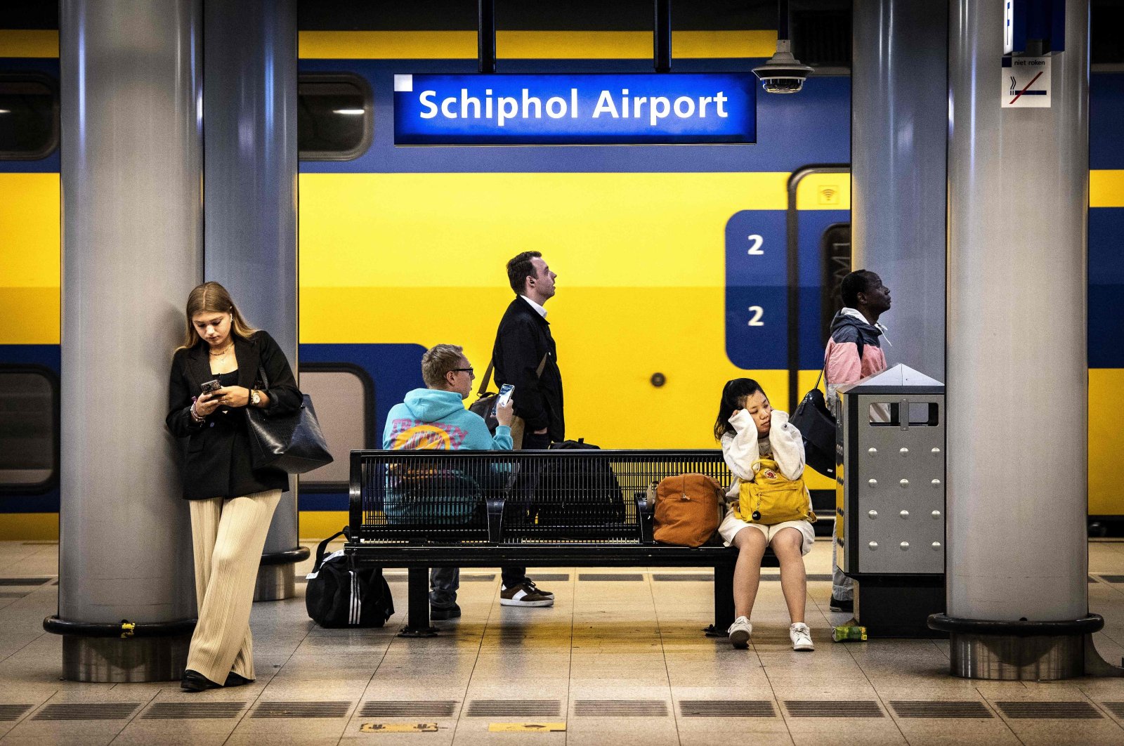 Travelers sit on a platform at the Schiphol Airport train station during a Dutch Railways strike, in Amsterdam, the Netherlands, Aug. 29, 2022. (AFP Photo)