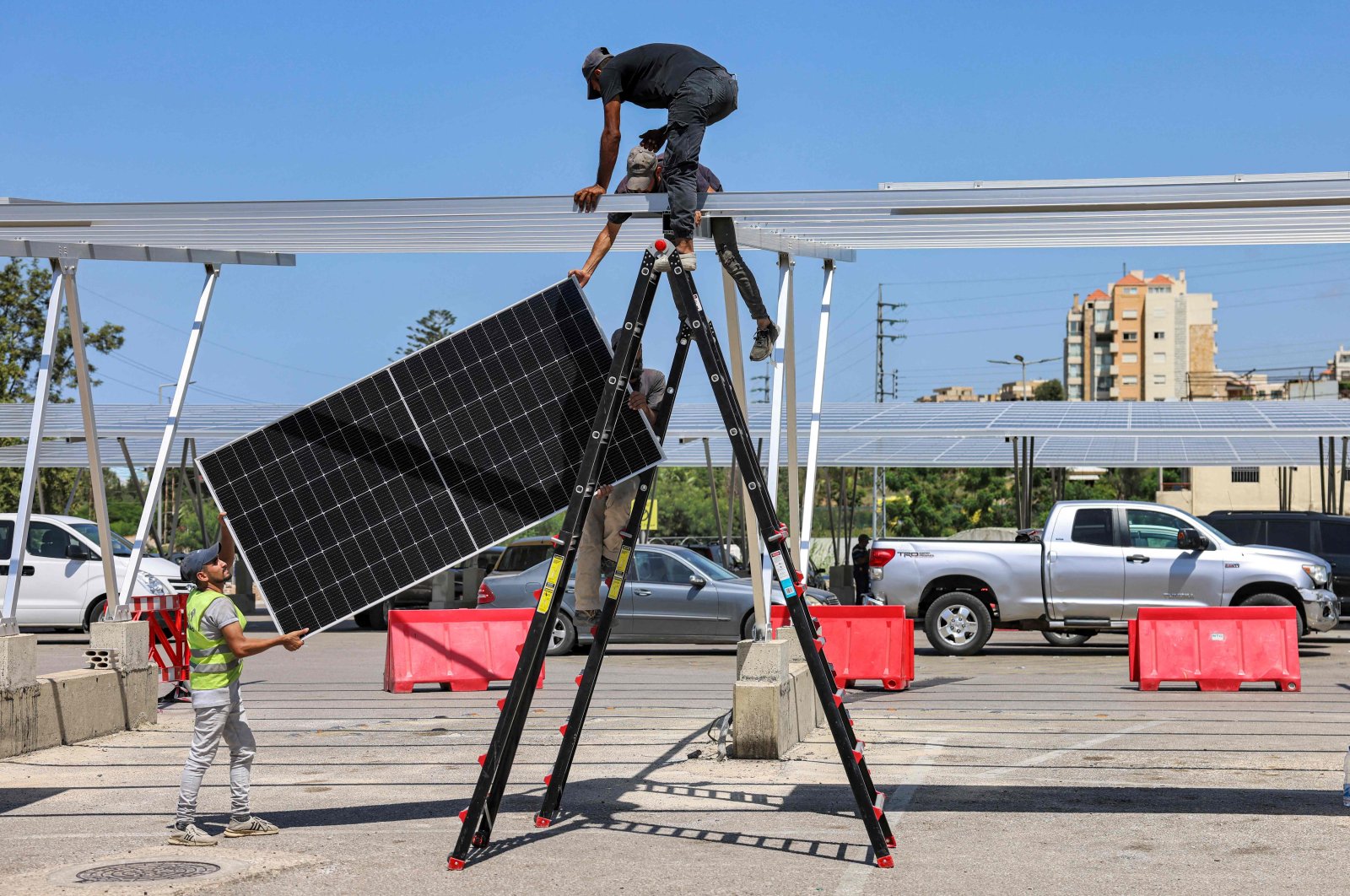 Workers install new solar panels that will also serve as shade for vehicles in the car park of a shopping mall in Byblos, northern Lebanon, Aug. 26, 2022. (AFP Photo)