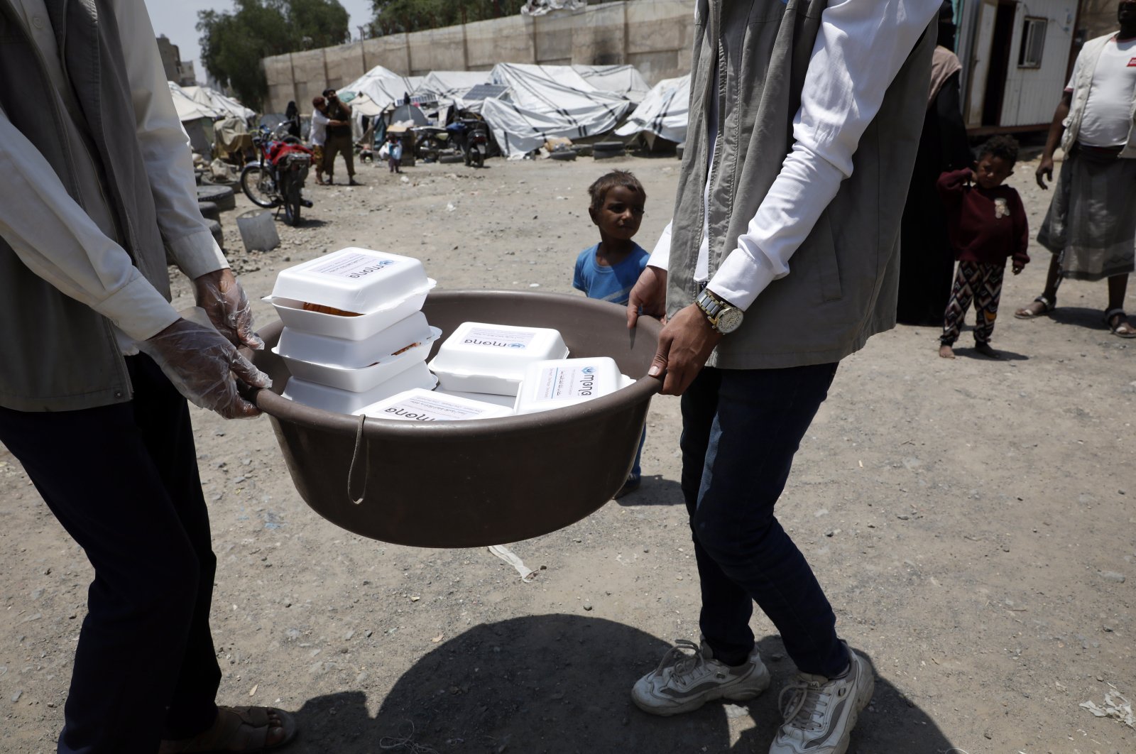 Volunteers distribute food provided by the Mona relief agency to displaced people at a makeshift camp on the International Day of Charity, in Sanaa, Yemen, Sept. 5, 2022. (EPA File Photo)