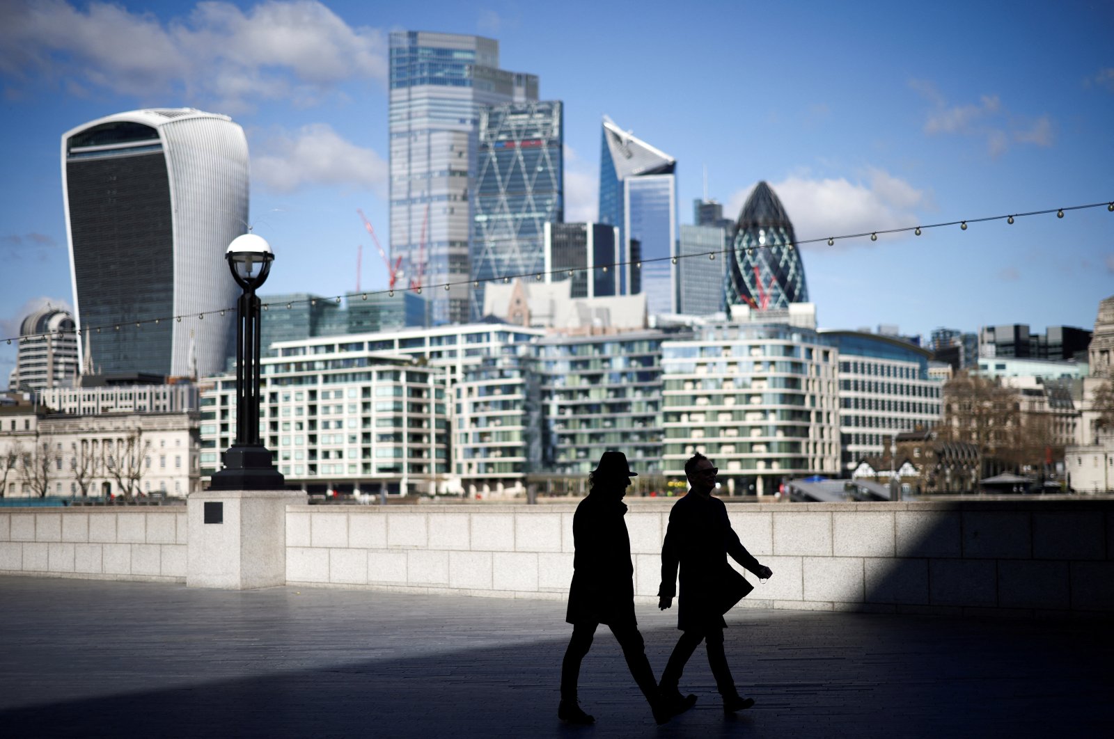 The City of London financial district can be seen as people walk along the south side of the River Thames, London, Britain, March 19, 2021. (Reuters Photo)