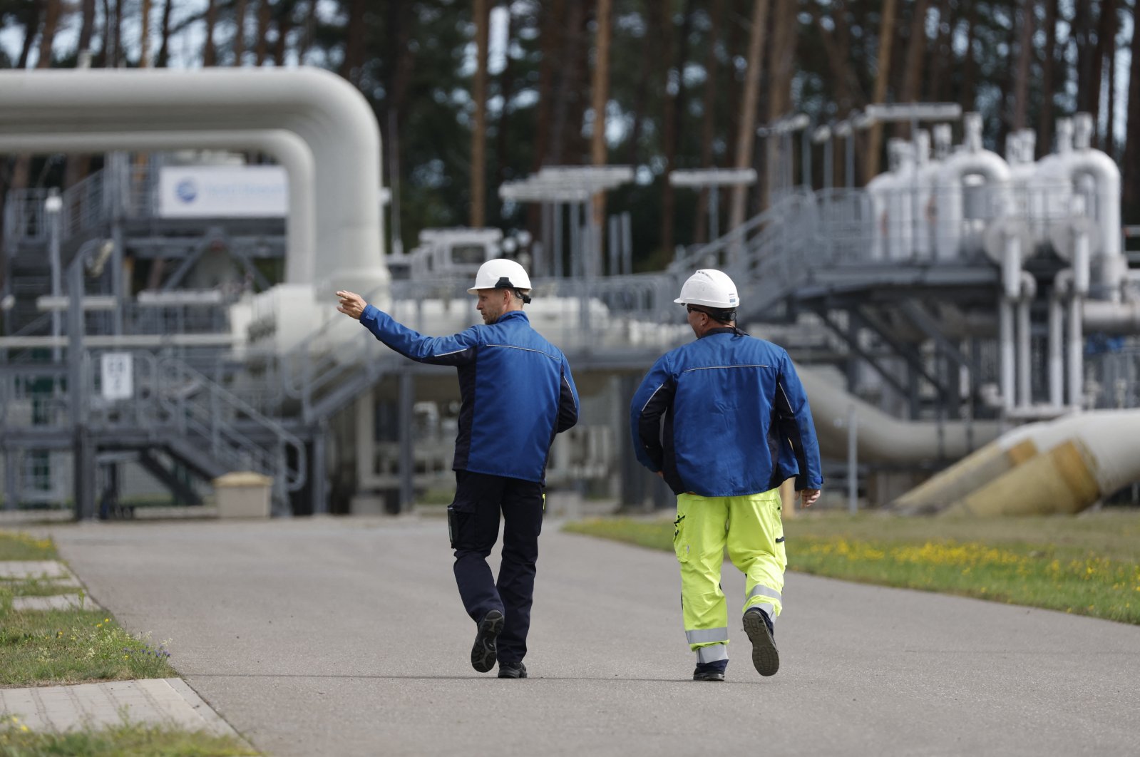 Workers walk past facilities to receive and distribute natural gas on the grounds of gas transport and pipeline network operator Gascade in Lubmin, northeastern Germany, close to the border with Poland, Aug. 30, 2022. (AFP Photo)
