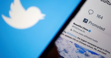 A Twitter logo is displayed on a mobile phone near a computer screen showing promoted tweets on China, in this illustration picture taken Sept. 8, 2022. (Reuters Photo)