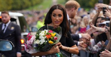Meghan, Duchess of Sussex collects flowers as she chats with well-wishers on the Long walk at Windsor Castle, two days after the death of Britain's Queen Elizabeth II at the age of 96, Berkshire, U.S., Sept.10, 2022. (AFP Photo)