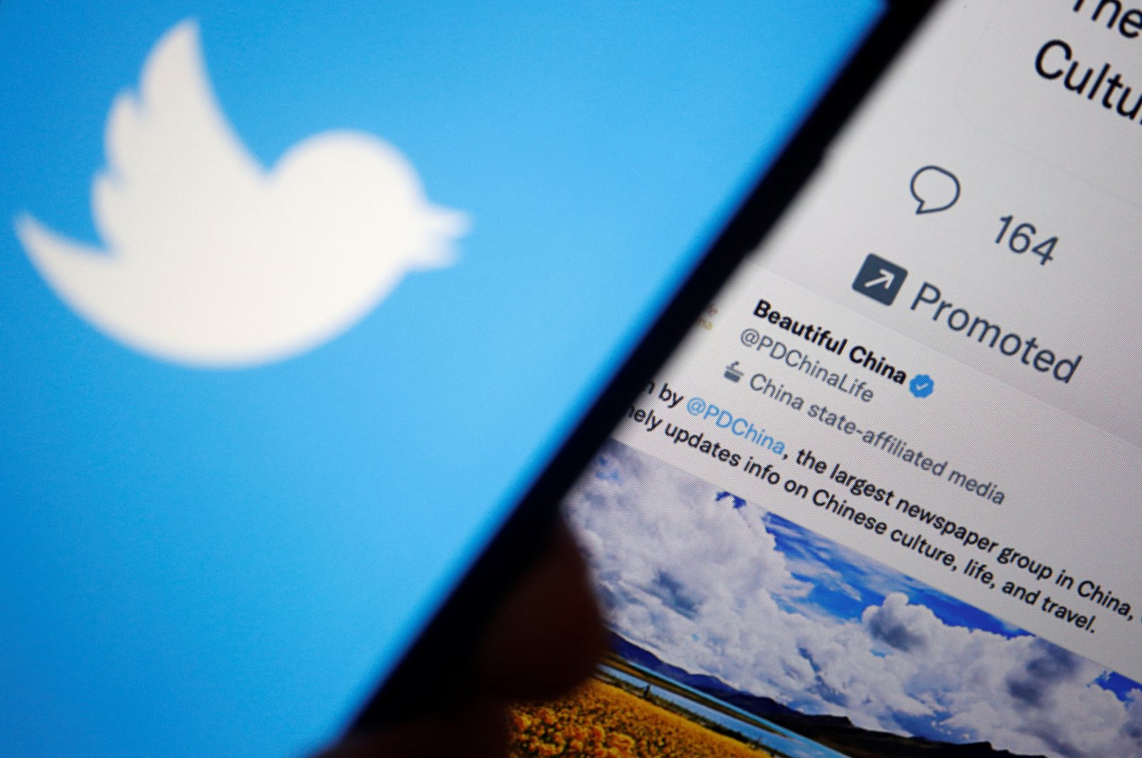 A Twitter logo is displayed on a mobile phone near a computer screen showing promoted tweets on China, in this illustration picture taken Sept. 8, 2022. (Reuters Photo)