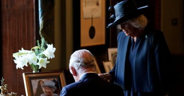 Britain's Camilla, Queen Consort (R), watches as Britain's King Charles III signs the visitors' book, alongside an image of his late mother Queen Elizabeth II, at Hillsborough Castle in Belfast, during his visit to Northern Ireland, Sept. 13, 2022. (AFP Photo)