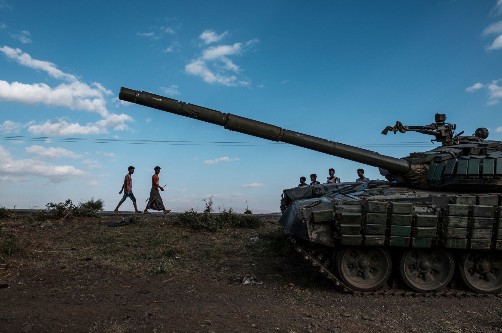 Youngsters walk next to an abandoned destroyed tank south of the town of Mehoni, Ethiopia, Dec. 11, 2020. (AFP Photo)
