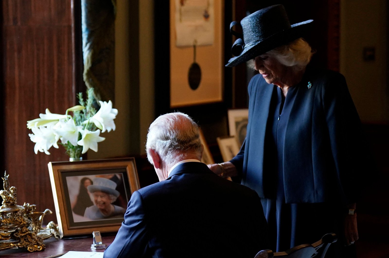 Britain&#039;s Camilla, Queen Consort (R), watches as Britain&#039;s King Charles III signs the visitors&#039; book, alongside an image of his late mother Queen Elizabeth II, at Hillsborough Castle in Belfast, during his visit to Northern Ireland, Sept. 13, 2022. (AFP Photo)