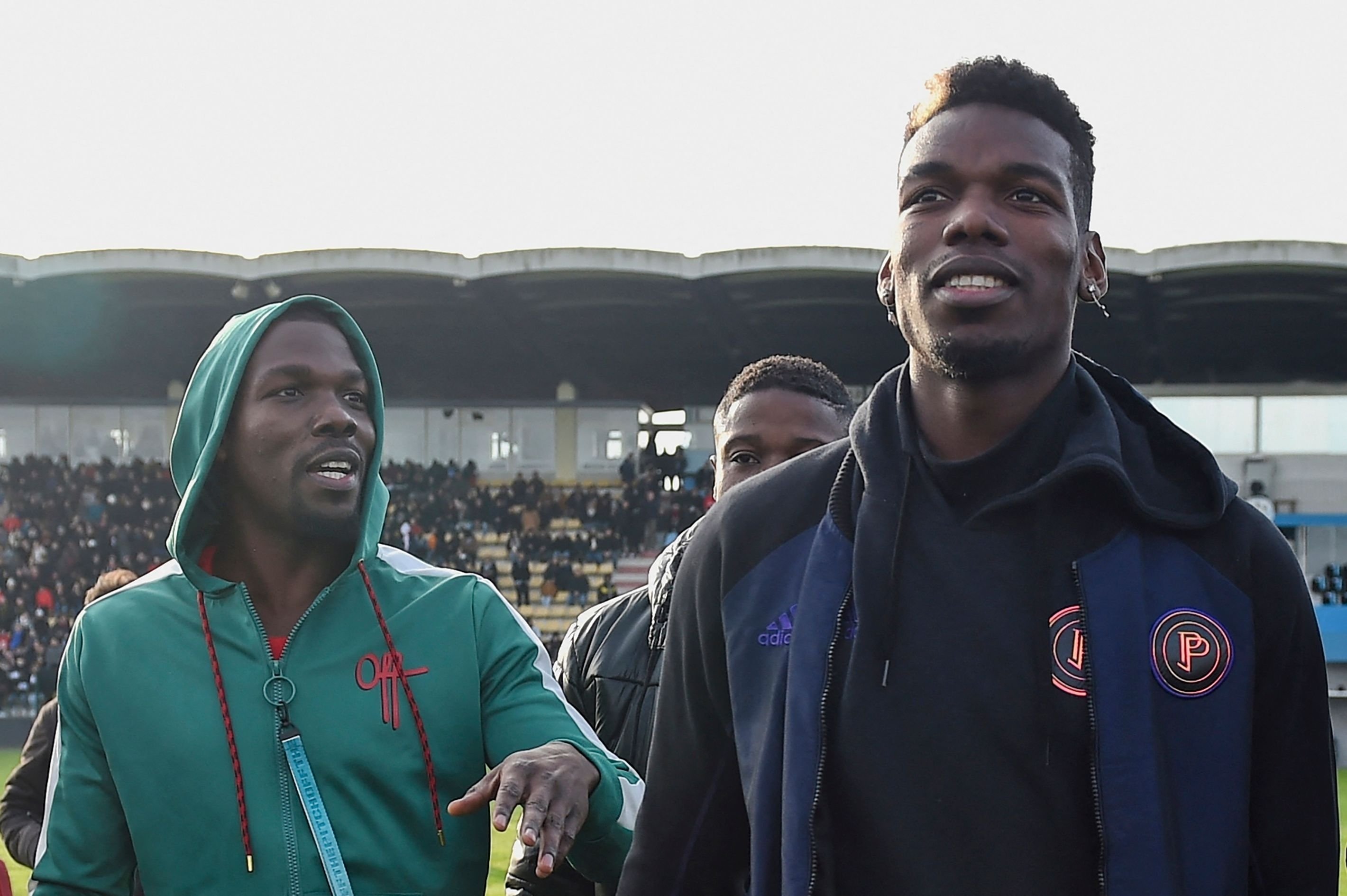 This file photo shows France national team player Paul Pogba (R) and his brother Mathias Pogba (L) walking on the pitch prior to a football match between All Star France and Guinea at the Vallee du Cher Stadium in Tours, central France, as part of the &quot;48h for Guinea&quot; charity event, Dec. 29, 2019. (Photo by GUILLAUME SOUVANT / AFP)