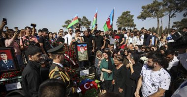 Azerbaijani people stand near the grave of serviceman Sabuhi Ahmadov during mass funerals of Azeri servicemen who were killed during clashes with Armenian troops on the border with Armenia, at the cemetery near Baku, Azerbaijan, Sept. 14, 2022. (EPA Photo)