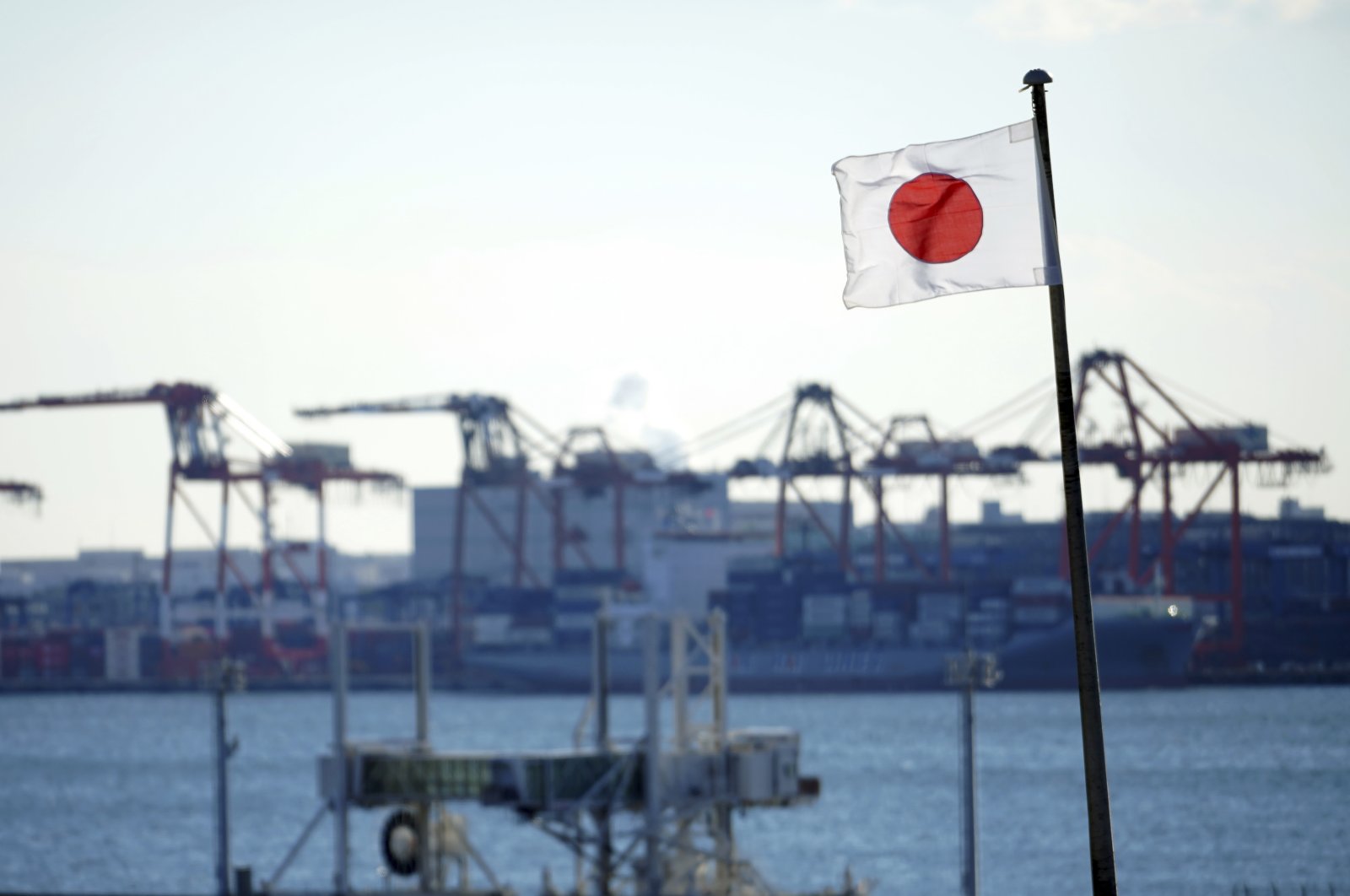 A national flag flies near a container port, in Tokyo, Japan, Jan. 20, 2022. (AP Photo)