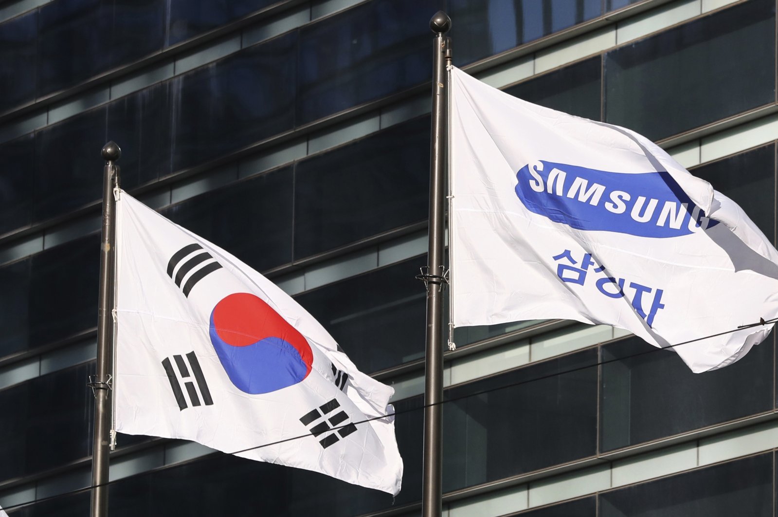 The company flag of Samsung Electronics (R) flutters next to the South Korean national flag in Seoul, South Korea, Jan. 16, 2017. (AP Photo)
