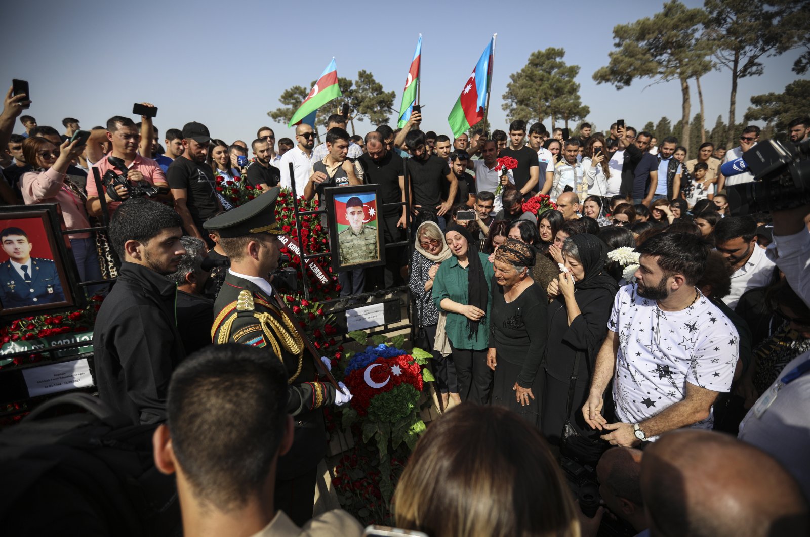 Azerbaijani people stand near the grave of serviceman Sabuhi Ahmadov during mass funerals of Azeri servicemen who were killed during clashes with Armenian troops on the border with Armenia, at the cemetery near Baku, Azerbaijan, Sept. 14, 2022. (EPA Photo)